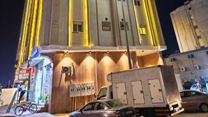 A multi-story building with illuminated vertical lines and a flat facade. - Al Rayhan Suites (Madinah)