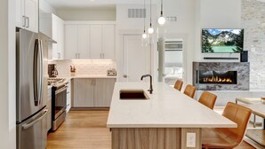 A modern kitchen with a central island, stainless steel appliances, and a fireplace.