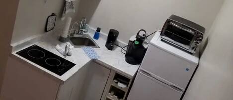 A compact kitchen with a stove, sink, and a small refrigerator.