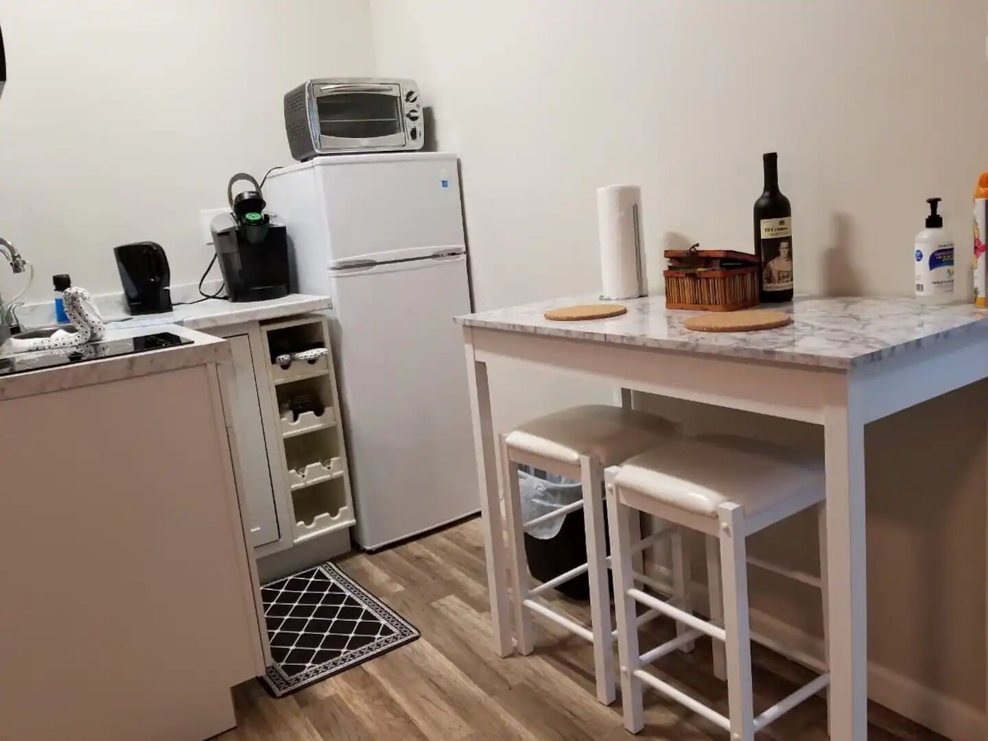 Cocina compacta equipada con microondas, refrigerador y una pequeña barra con taburetes.