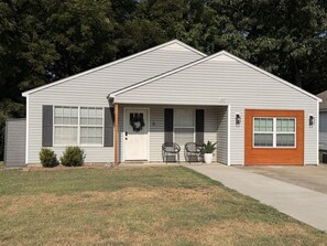A single-story house with a front porch, a mailbox, and a small garden area.