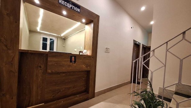 A reception area with a wooden reception desk, a large mirror, and a sign that reads "RECEPTION". - Hotel Yogita Inn  (Gaya)