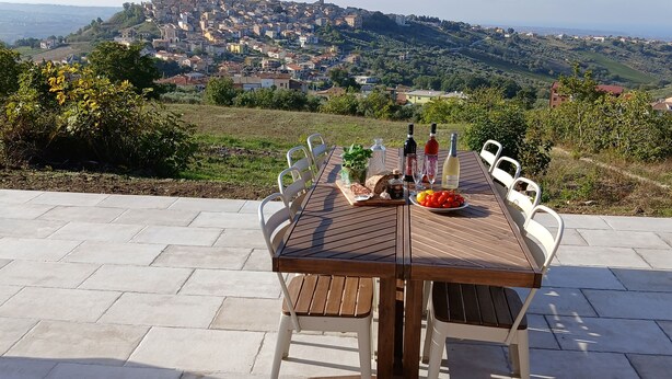 An outdoor dining table with a scenic view of a hilltop town.