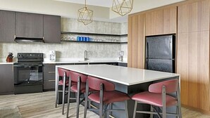 A modern kitchen with a central island, bar stools, a built-in oven, and a refrigerator. - Luxury Wyndham Margaritaville suite with short walk to football game fullKitchen (Atlanta)