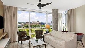 A hotel room with a large window, a ceiling fan, a sofa, two armchairs, a coffee table, and a TV. - Luxury Wyndham Margaritaville suite with short walk to football game fullKitchen (Atlanta)