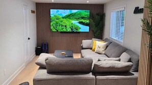 Un salon moderne avec un grand téléviseur à écran plat, un canapé gris et une petite table basse.