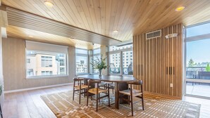 A modern dining area with a round table, chairs, and a view of the city through large windows. - Loft | Gym, Lounge | Bellevue | Sophari Downtown A (Bellevue)