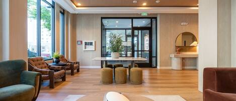 A lobby with leather sofas, a central table, a large white sculpture, and a mirror.