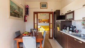 Une cuisine moderne avec un coin repas, comprenant une table en bois, des chaises et un panier de fruits.
