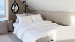Un dormitorio con una cama, almohadas, una alfombra, un espejo redondo y una lámpara en el techo.