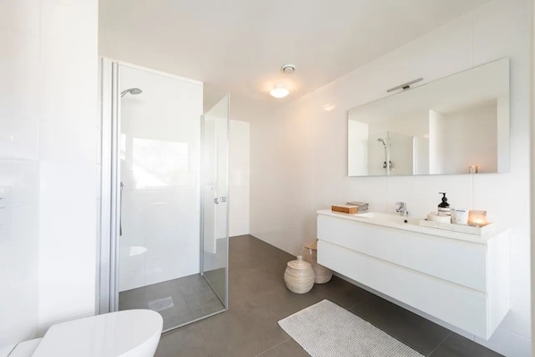 A modern bathroom with a glass shower enclosure, a white vanity with a large mirror, and a white toilet. - Fjord View Apartment - 20 min Drive to Pulpit Rock (Rogaland)