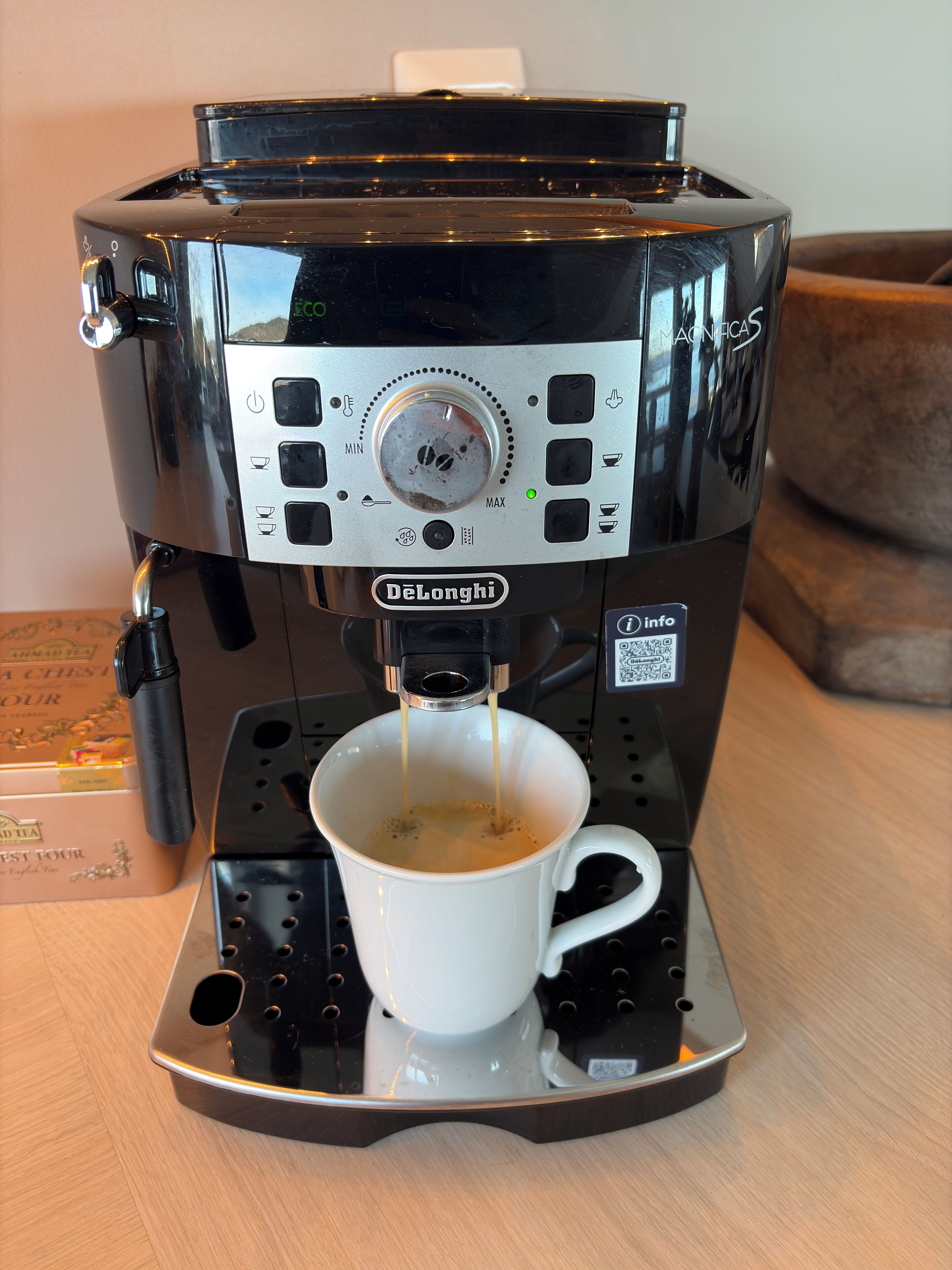 A De'Longhi espresso machine with a white cup underneath, dispensing coffee.