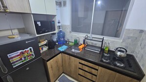 Una cocina compacta equipada con microondas, dispensador de agua, hervidor y cocina a gas.