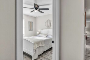 A bedroom with a bed, a ceiling fan, a bedside table, and a wall-mounted circular object.