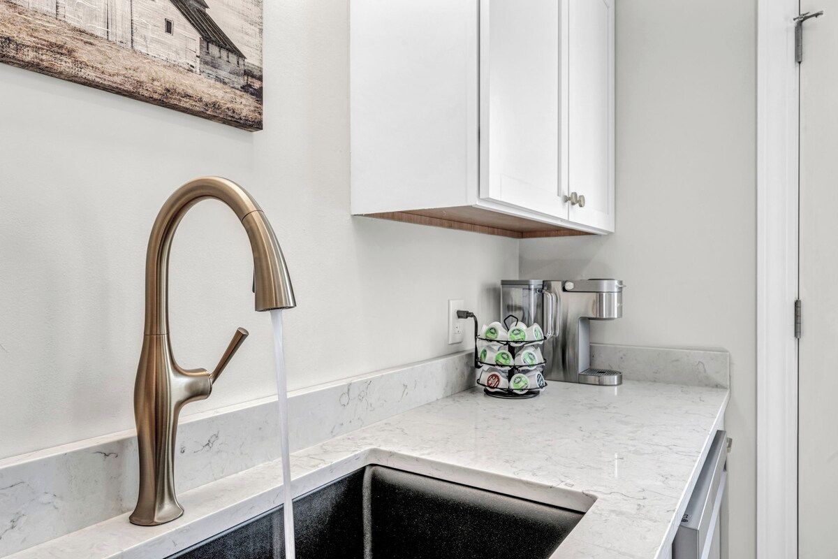 A modern kitchen with a single sink, a coffee machine, and a cabinet above the counter.