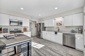 A modern kitchen with white cabinetry, stainless steel appliances, and a striped countertop.