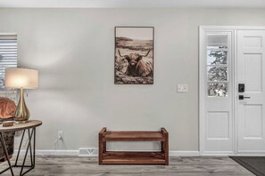 A room with a wooden bench, a lamp, and a framed picture on the wall.