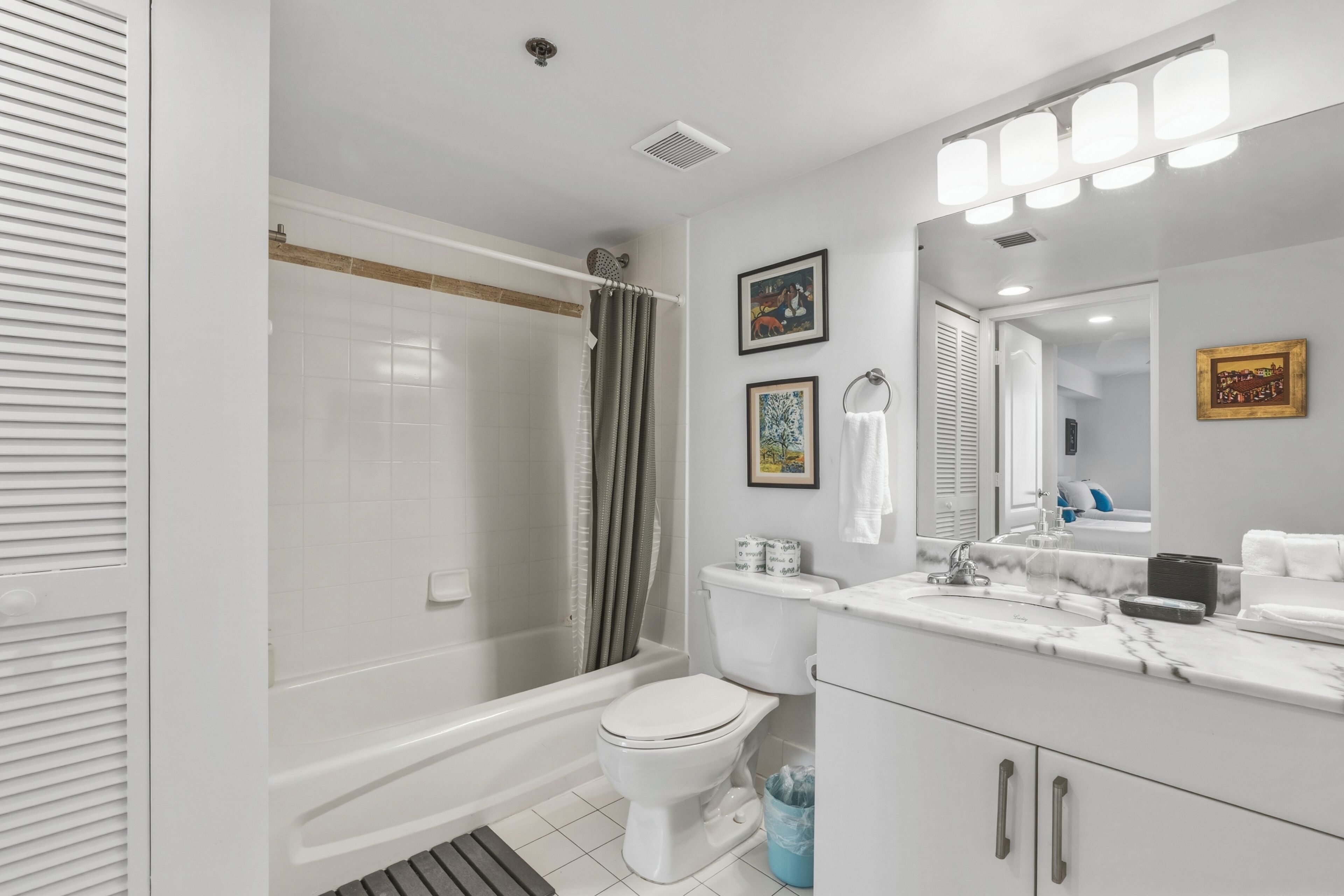 A bathroom with a bathtub, toilet, vanity with a mirror, and a shower curtain.