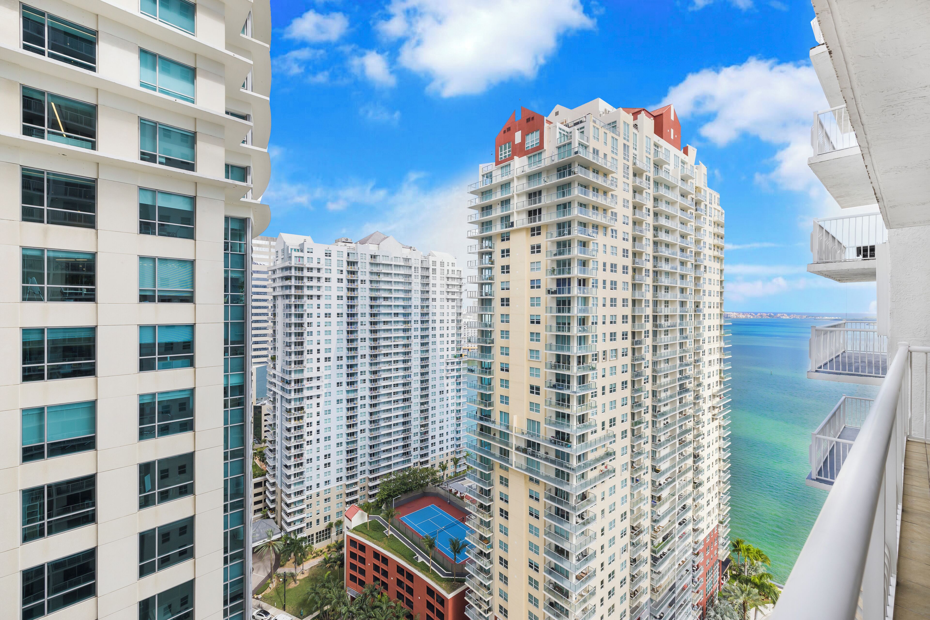 A high-rise residential building with multiple balconies, a rooftop pool, and a view of the ocean.