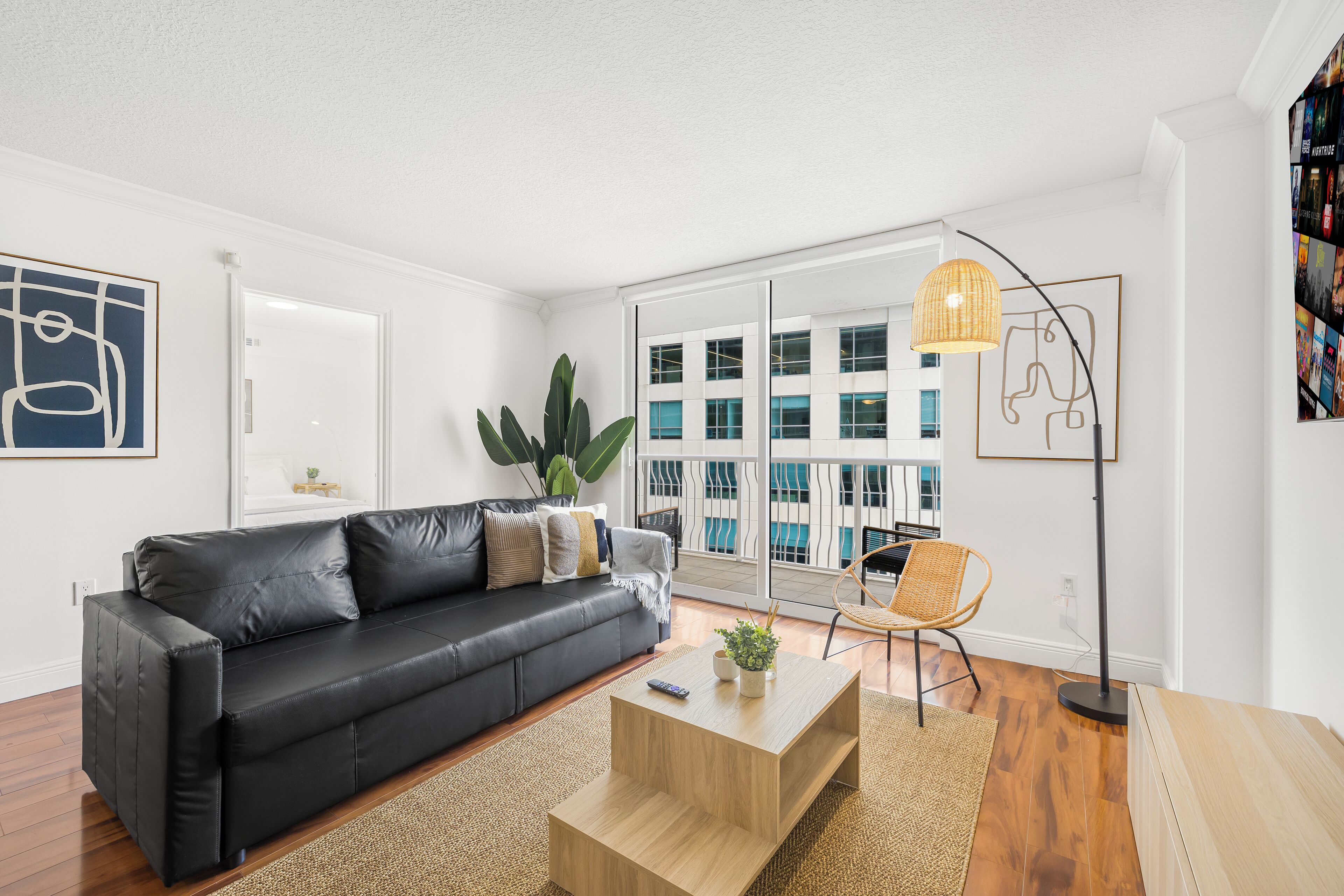 A modern living room with a black leather sofa, a wooden coffee table, and a floor lamp.