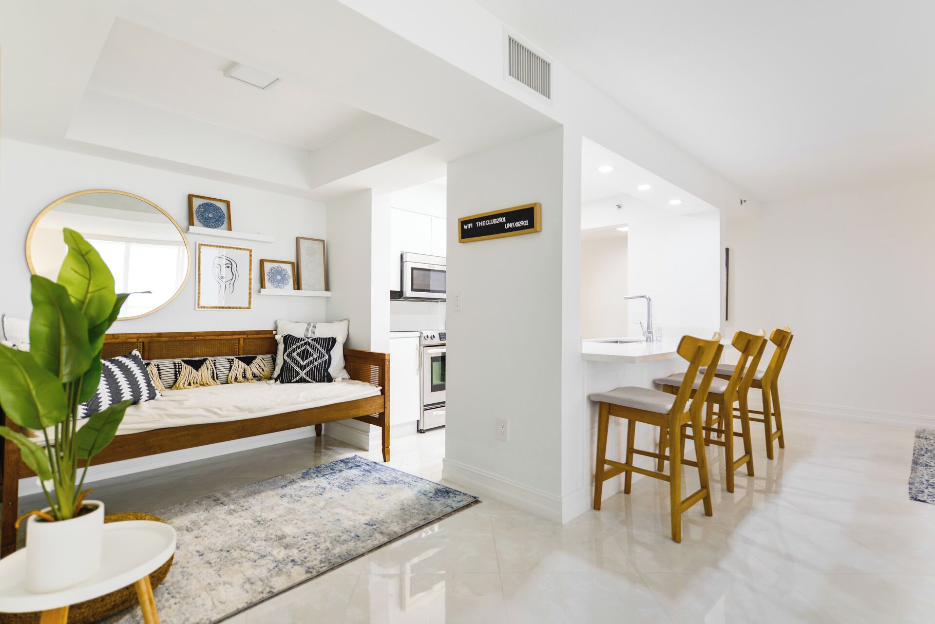 Una sala de estar moderna con un sofá, un comedor con sillas, una cocina y un espejo grande.
