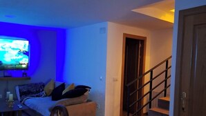 Sala de estar con televisor, sofá y comedor.