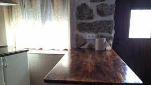 Una cocina con una pared de acento de piedra, encimera de madera y una ventana con cortinas.