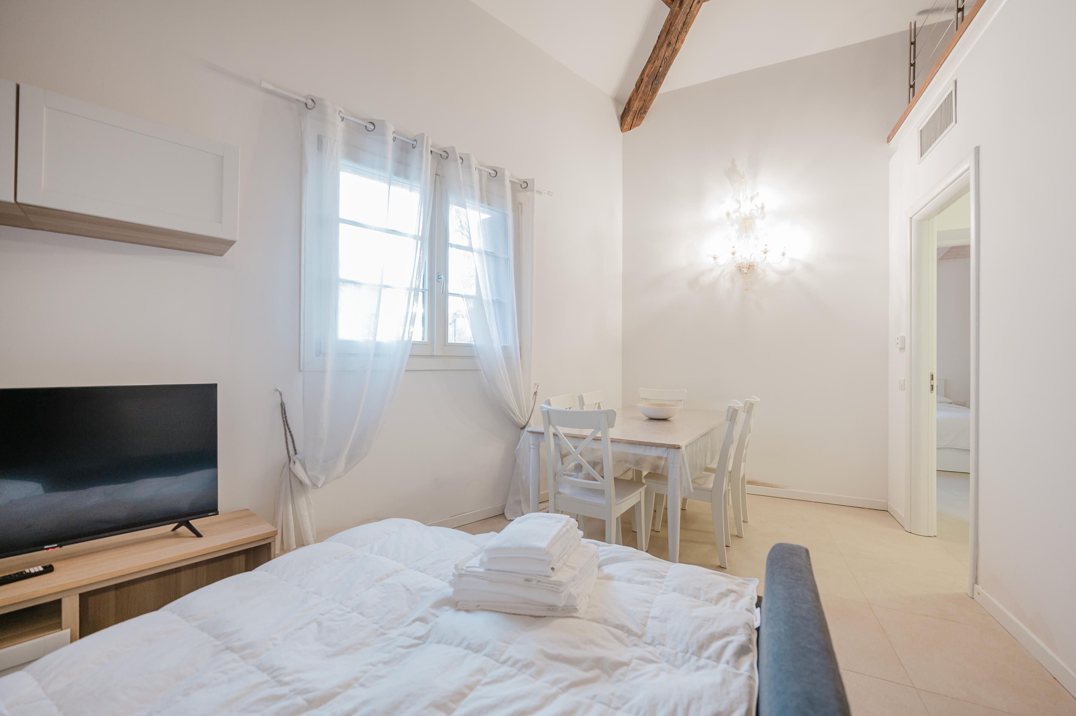 Een slaapkamer met een bed, een televisie, een bureau en een stoel.