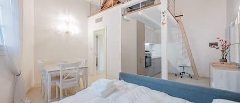 Un dormitorio con literas, un escritorio y una silla. Una escalera conduce a un nivel superior.