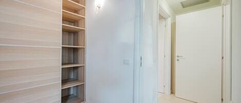 A modern room with built-in wooden shelving, a white door, and a ceiling light fixture.
