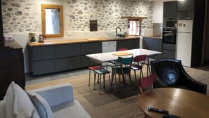 A compact kitchen with a stone wall, a wooden countertop, and a dining area with a table and chairs.
