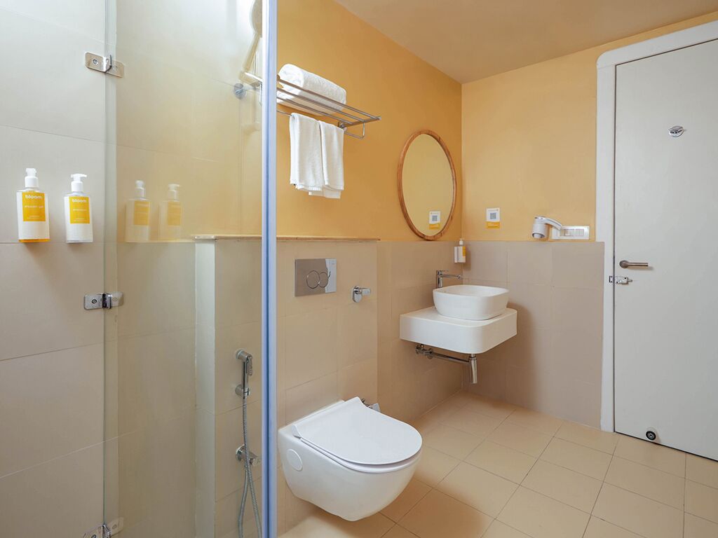Un bagno moderno con box doccia in vetro, un water bianco, un lavandino con specchio e articoli da toilette a parete.