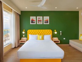 Una camera d'albergo con un letto grande, pareti verdi e tre quadri appesi al muro.