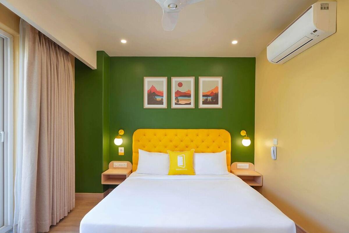 Una habitación de hotel con una cama grande, paredes verdes y un ventilador de techo.