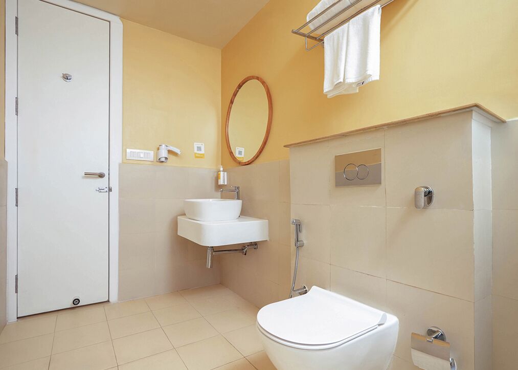 A bathroom with a toilet, sink, and mirror.