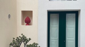Ein Gebäude mit einer grünen Tür, einem Fenster mit Gitterstäben und einem Blumentopf.