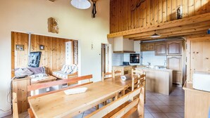 Un interior de madera con comedor, cocina y un altillo.