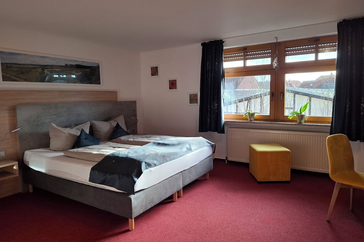 A bedroom with a bed, a window with a view, a radiator, and a chair.