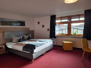 A bedroom with a bed, a window with a view, a radiator, and a chair. - Hotel Bike & Hike (Wildeck)