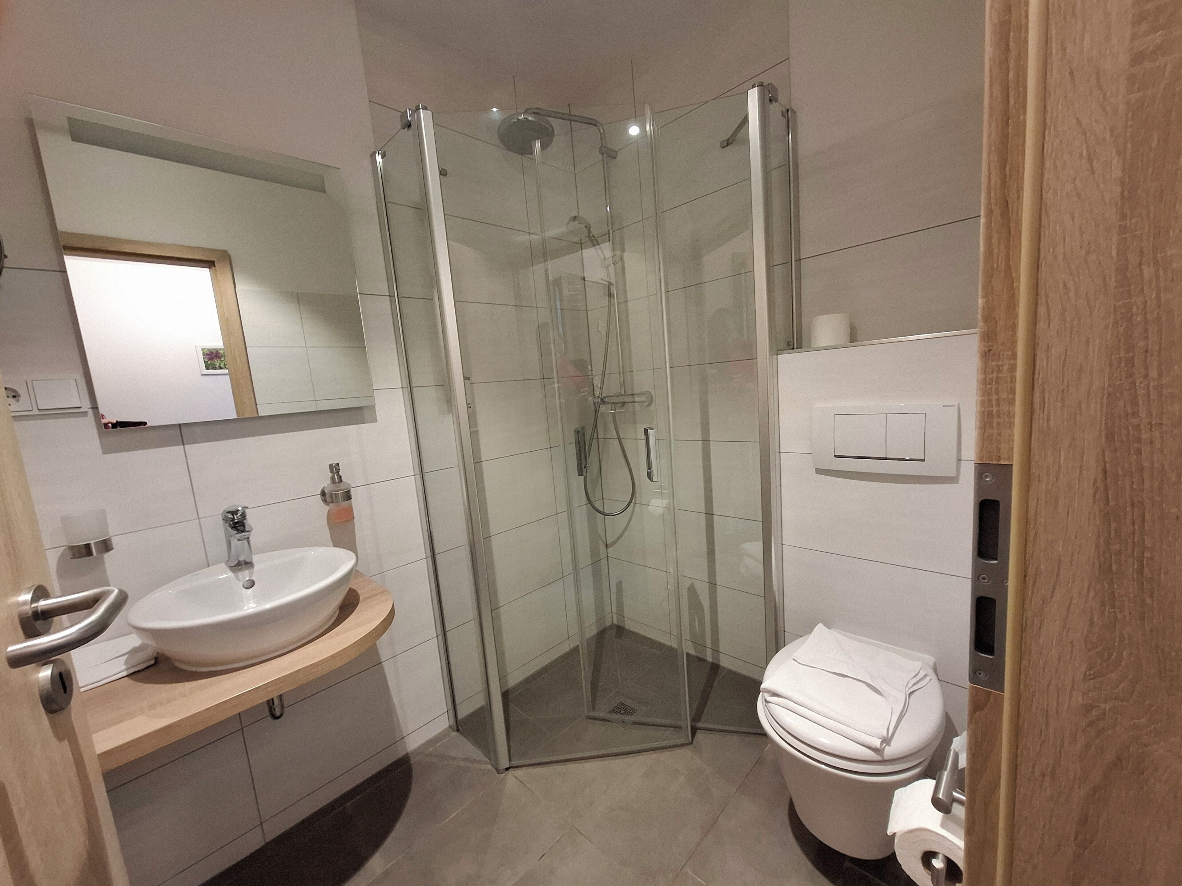 Une salle de bain moderne avec une douche à parois de verre, un lavabo avec un miroir et des toilettes.