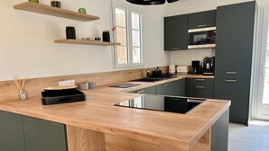 Una cocina moderna con armarios oscuros, encimera de madera y microondas empotrado.