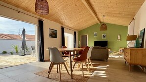 Un salón amplio con techo alto, una mesa de comedor con sillas, un sofá y una televisión.