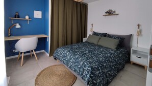 Un dormitorio con cama, escritorio, silla y lámpara colgante.