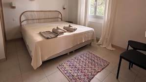 A bedroom with a bed, a window with curtains, a rug, and wall decor. - Mini Villa near Pinarello beach (Zonza)
