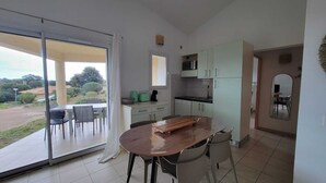 A modern kitchen with a dining area, sliding glass doors leading to a patio, and a view of the outdoors. - Mini Villa near Pinarello beach (Zonza)