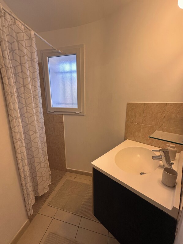 A bathroom with a shower, a sink with a glass shelf, and a window with frosted glass. - Mini Villa near Pinarello beach (Zonza)