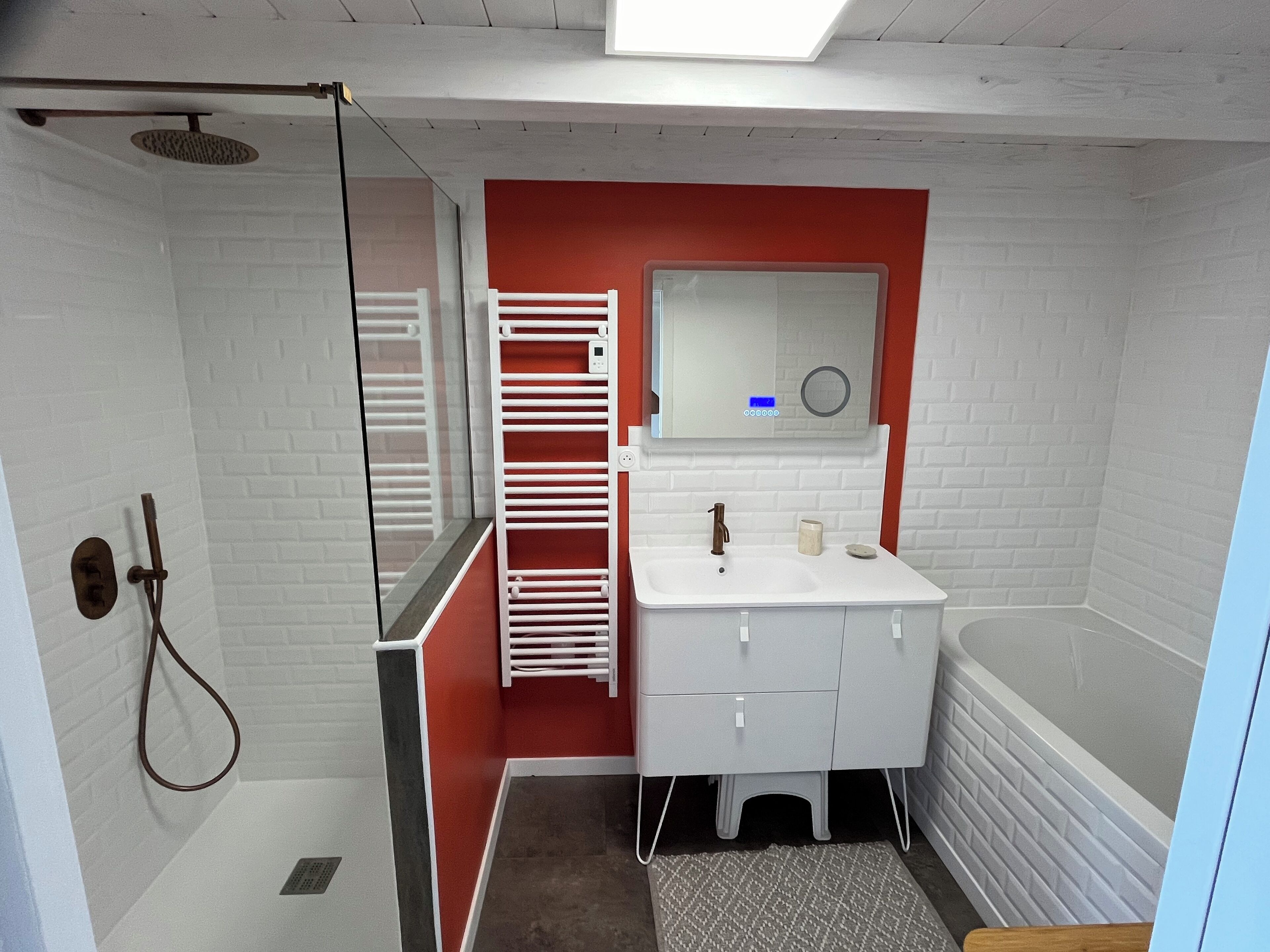 Un baño moderno con lavamanos, espejo y ducha blancos.