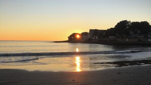 A beach with a sunset, calm water, and buildings in the background. - Cosy, comfortable 4-star apartment (Vaux-sur-Mer)