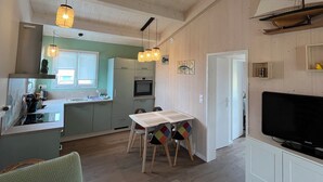 A modern kitchen with a dining area, a television, and a wooden ceiling. - Cosy, comfortable 4-star apartment (Vaux-sur-Mer)