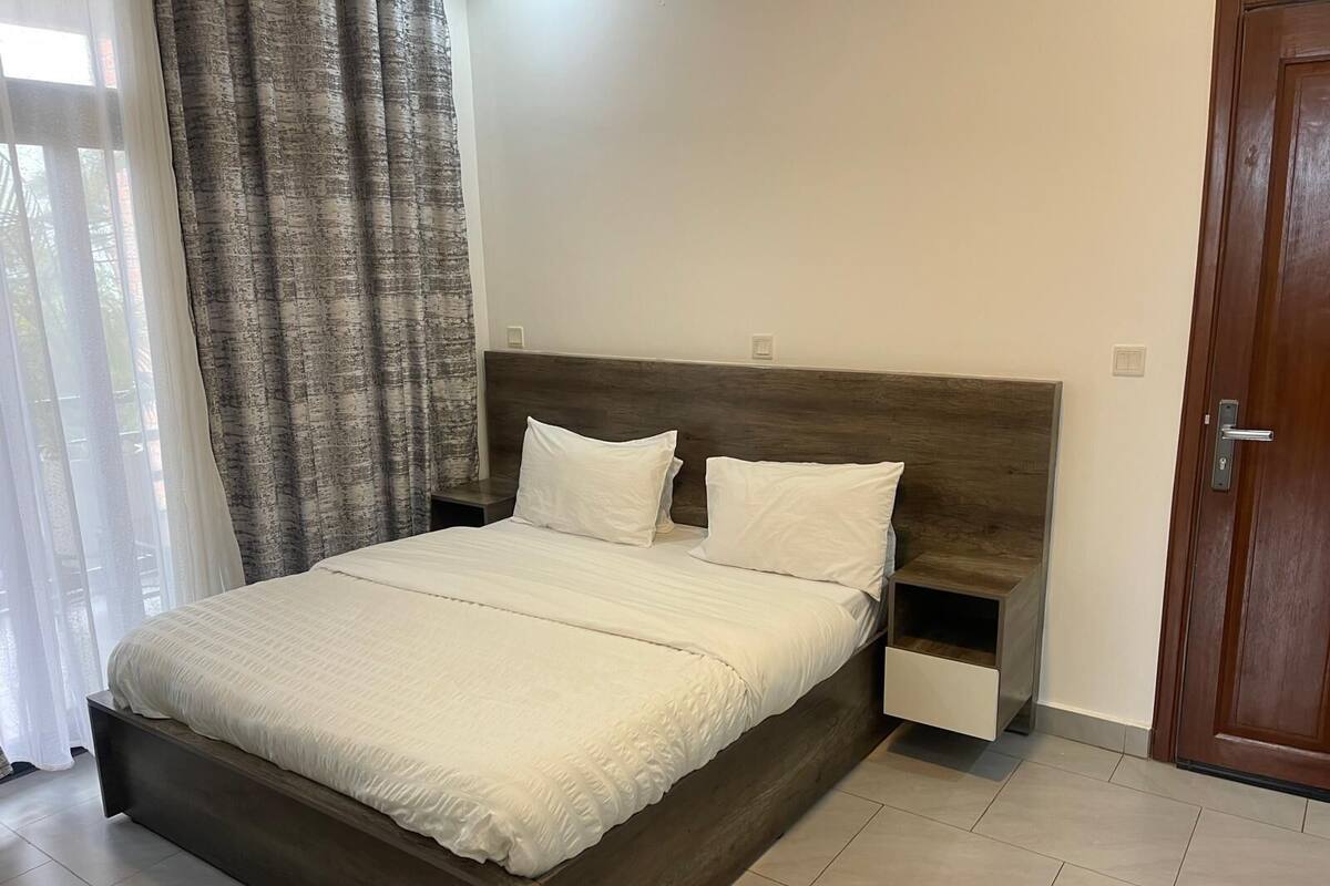 A modern bedroom with a wooden bed frame, white bedding, and a nightstand.